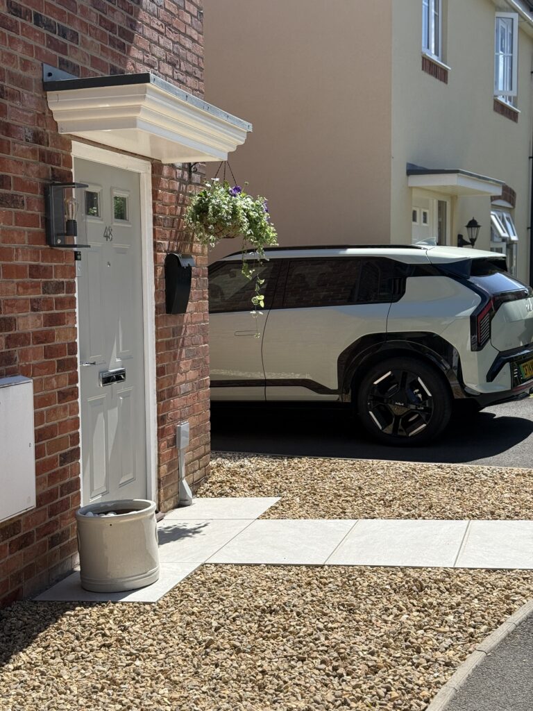 Front entrance with porcelain pathway tiles, decorative gravel, hanging basket and planter.