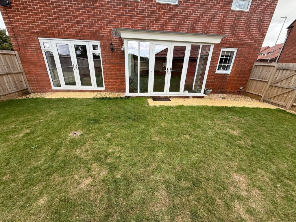Rear garden before landscaping with uneven lawn and minimal patio area