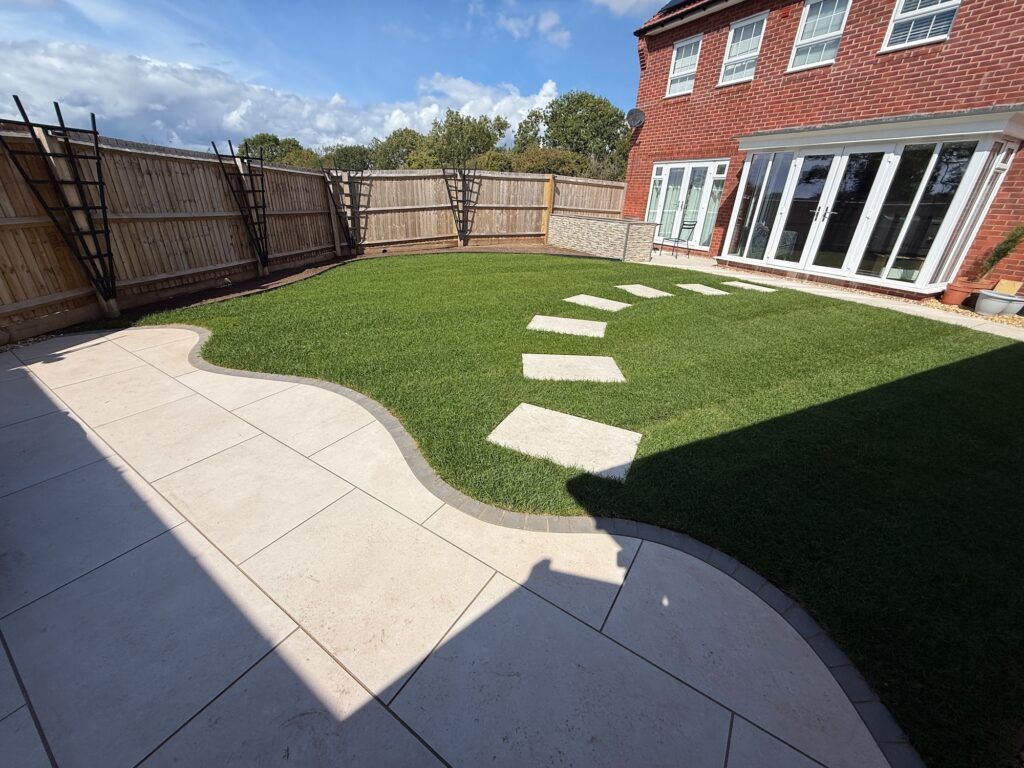Transformed rear garden with curved porcelain patio and artificial grass lawn