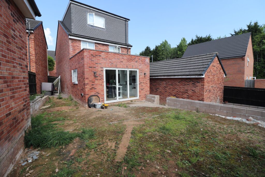 Rear garden before landscaping with uneven terrain and no patio or lawn