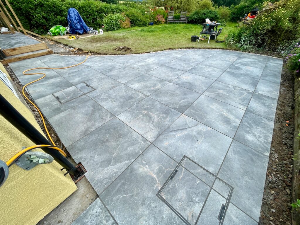 After image of large-format porcelain patio installed in a landscaped garden